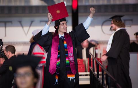 Image of graduate holding up their diploma at the Undergraduate Ceremony