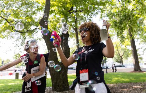 Image of MIT Alumni Association staff members with small bubble machines cheering on the graduates the morning of the Undergraduate Ceremony