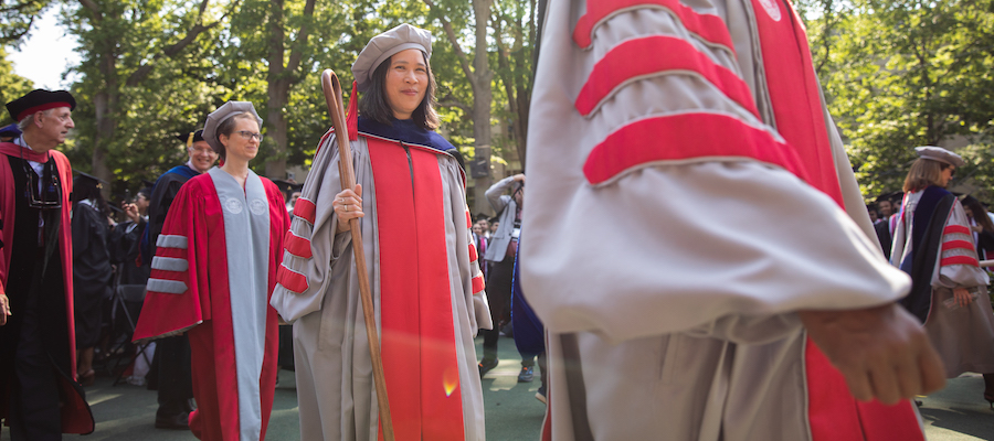 Image of Lily Tsai carrying the ceremonial crook. She is wearing her regalia. 
