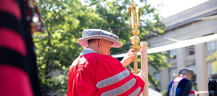Image of Stephen Baker placing the ceremonial mace in it's holder at the start of the OneMIT Ceremony