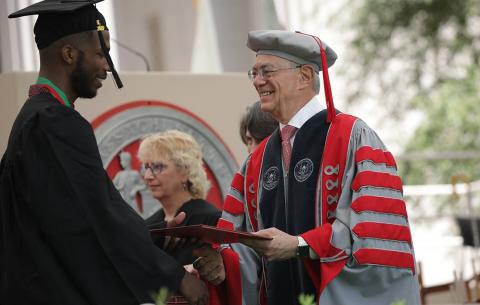 President Rafael Reif hands a diploma to a student