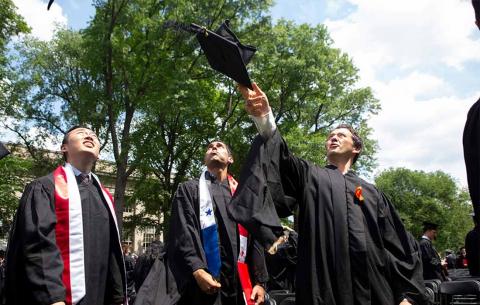 Graduates toss their cap into the air