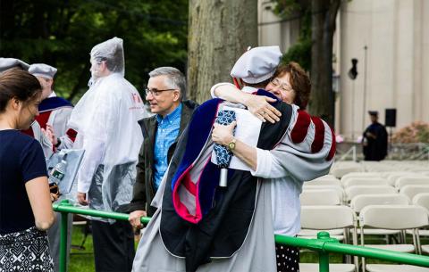 A new PhD embraces a family member after the ceremony; photo: Jake Belcher