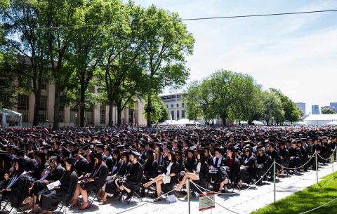 Graduates sit in Killian Court on a sunny Commencement day