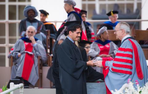 Image of a student receiving their Congratulations Scroll from President Reif