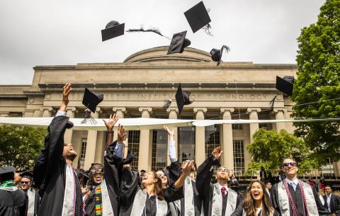 Image of graduates throwing their caps in the air in front of the Dome 