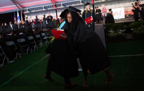 Image of graduates hugging after receiving their diplomas at the Undergraduate Ceremony
