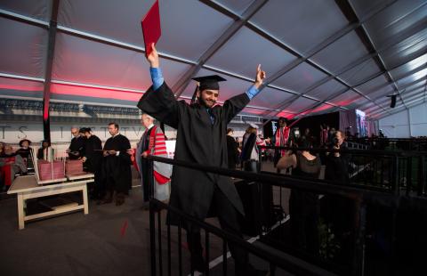 Image of graduate holding up their diploma at the Undergraduate Ceremony