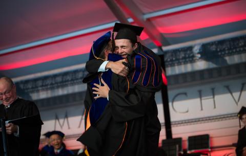 Image of a graduate hugging a professor at the Undergraduate Ceremony