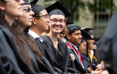Image of graduates in the audience smiling at each other