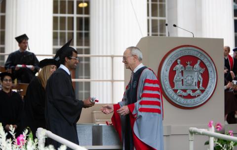 Image of President Reif handing a Congratulations scroll to a graduate