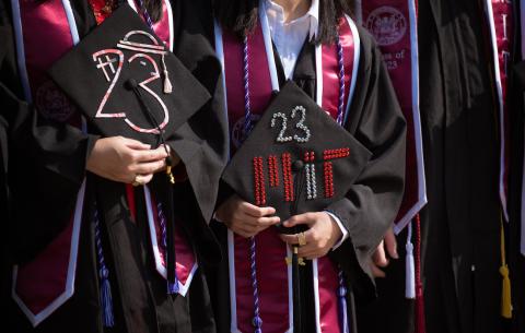 Image of Undergraduate Students holding their decorated caps which have a bedazzled 23 on them