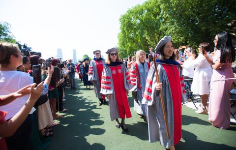 Image of the academic procession making it's way down the center aisle in Killian Court. Lily Tsai is leading the procession with Provost Cindy Barnhart (right) and President Sally Kornbluth (left) behind her.