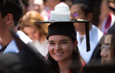 Image of a graduate smiling with her decorated cap that shows a small-scale version of the Lobby 10 dome