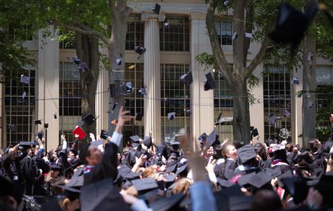 Image of graduates throwing their caps in the air following the diploma distribution