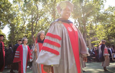 Image of Chancellor Melissa Nobles walking during the academic procession, Lily Tsai is seen behind her holding the crook
