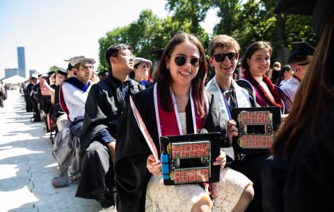 Image of graduates seated in the audience showing their grad caps decorated with Mark Rober's name