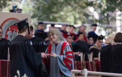 Image of President Sally Korbluth handing a diploma to an undergraduate student
