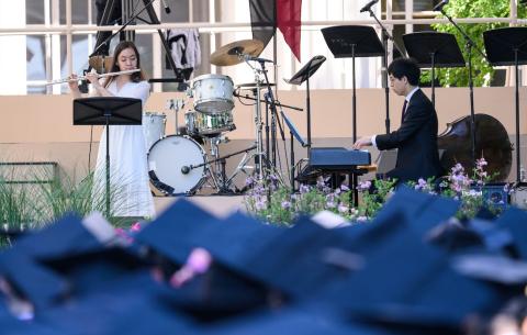 Image of Phoebe C. Lin playing a solo on her flute during the Undergraduate Ceremony