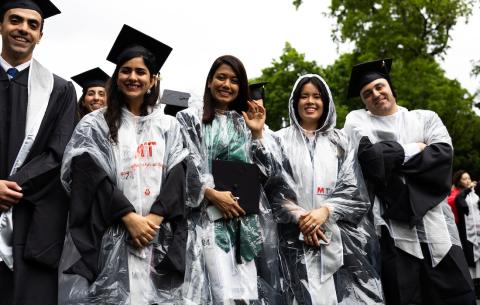 Image of graduates in their regalia and rain ponchos before the OneMIT Commencement Ceremony